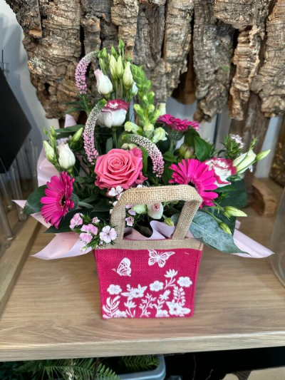 Sweet Surprise - A vibrant flower bag filled with bold pinks, crisp whites and touches of purple, finished with fresh greenery.